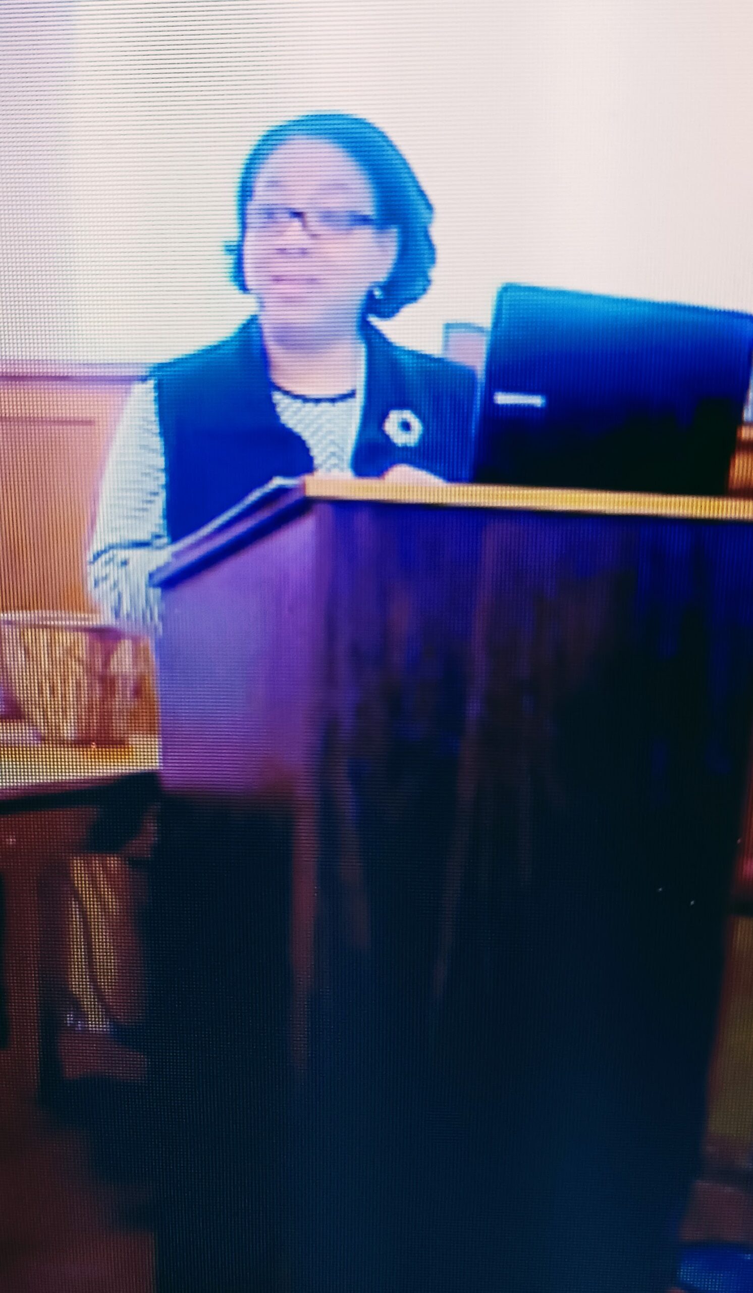 Maya Claire Todd, a professional educator with a master's degree from Indiana University, standing at a lectern in a teaching environment.